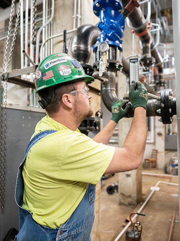 Nate Zirkle, McElroy’s construction division plumber/pipefitter, tightens bolts on an iron piping connection.