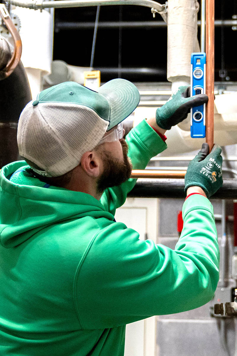 Brent Eisenbarth checks the alignment of copper piping he has installed for a McElroy’s commercial construction customer.